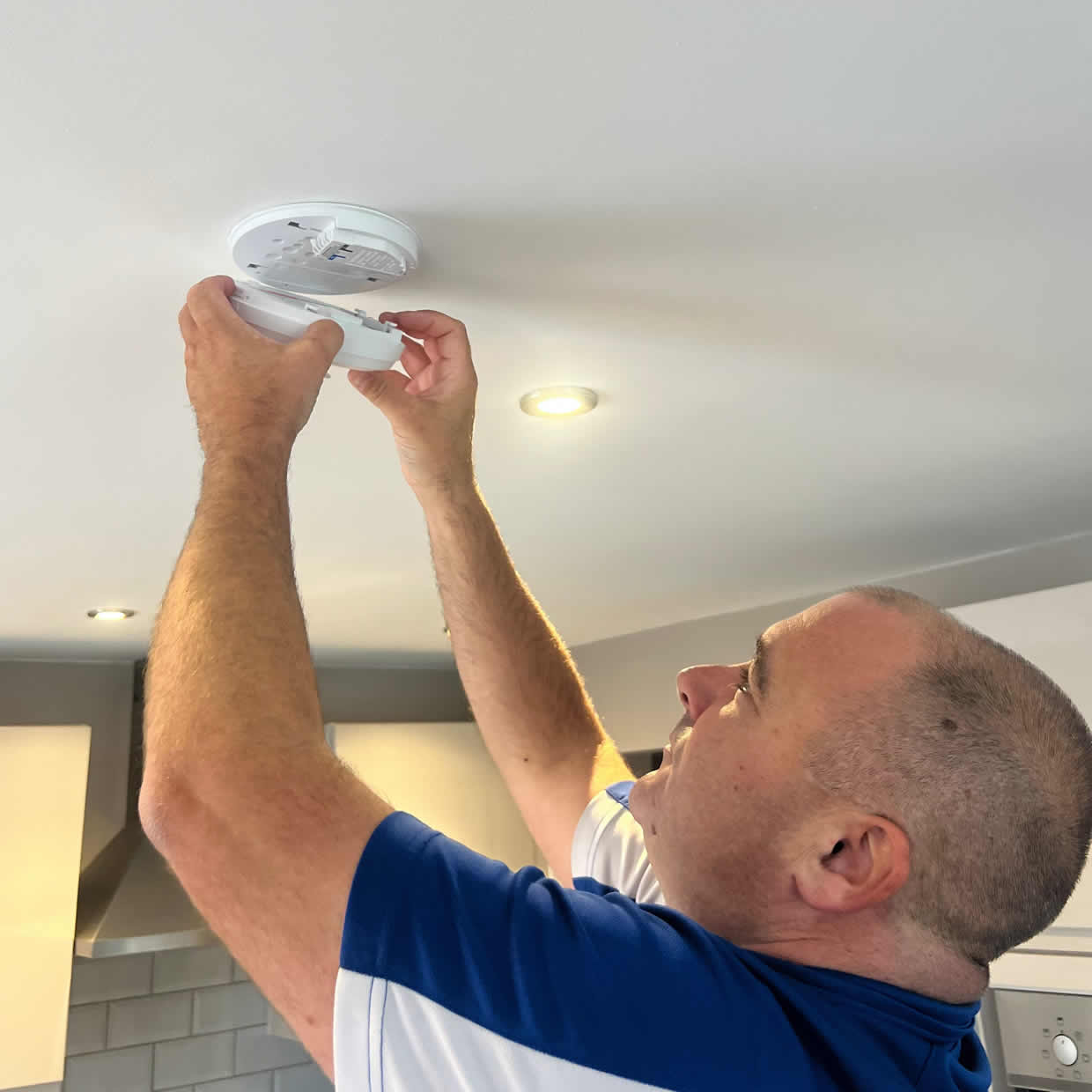Smoke alarm installer fitting an alarm in a Northwich property